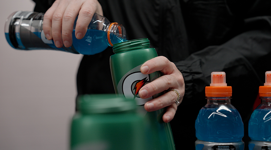 Athlete pouring Gatorade sports drink into personalized Gx bottle system for customized hydration based on individual sweat test results and electrolyte replacement needs